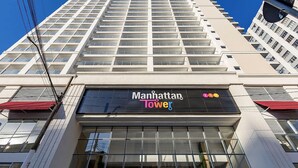 Ein Hochhaus mit einem Schild, auf dem 'Manhattan Tower' steht.