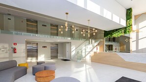 Eine moderne Lobby mit einer Glastreppe, Sitzbereichen und einem Feuerlöscher.