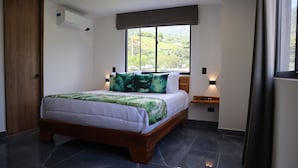 A bedroom with a bed, a window, a nightstand, and a wall-mounted air conditioner.