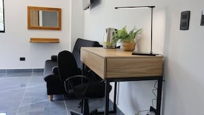 A modern office space with a wooden desk, black office chair, and a standing lamp.