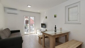 Ein modernes Wohnzimmer mit einer Couch, einem Esstisch und einem Fernseher.