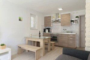 Une cuisine compacte avec des meubles en bois, un four encastré et un coin repas équipé d’une banquette.