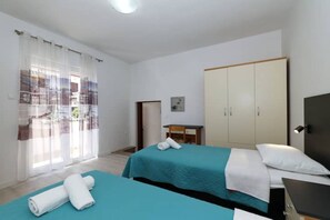 Ett hotellrum med två sängar, ett skrivbord, en garderob och ett fönster med gardiner.