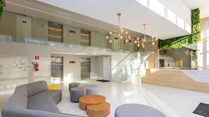 Eine moderne Lobby mit Treppe, Sitzbereichen und einem Feuerlöscher.