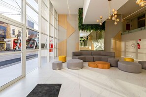 Un intérieur moderne avec de grandes fenêtres, un canapé d’angle et un luminaire au plafond original.