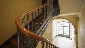 Escadaria de madeira com balaústres decorados que dá acesso a um andar superior.