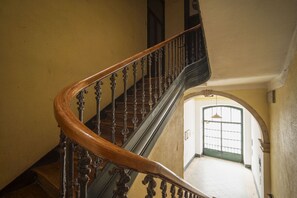 Eine hölzerne Treppe mit aufwendig gestalteten Geländern, die zu einer oberen Etage führt.