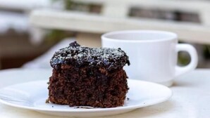 A slice of chocolate cake on a white plate on a white table.