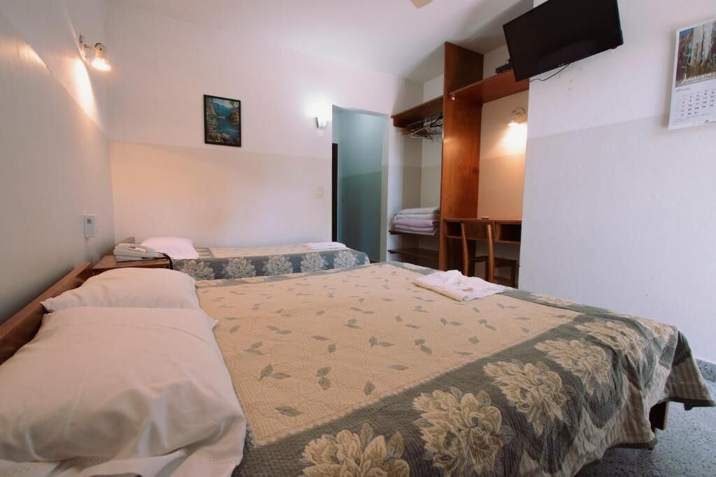 Habitació d'hotel amb dos llits, una taula de treball i una televisió.