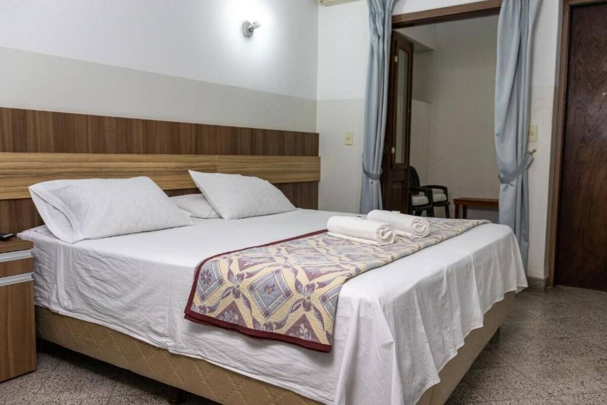A neatly made bed with a patterned blanket, a wooden headboard, and a small bedside table.