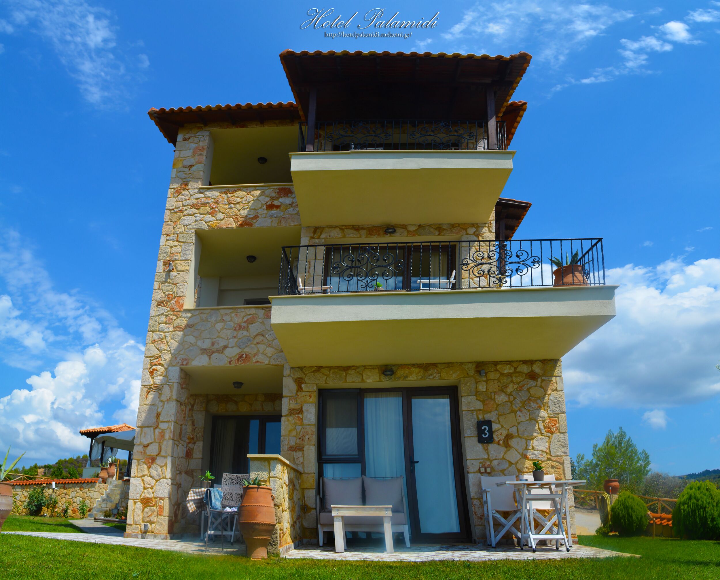 A multi-story hotel with stone facade, balconies, and outdoor seating.
