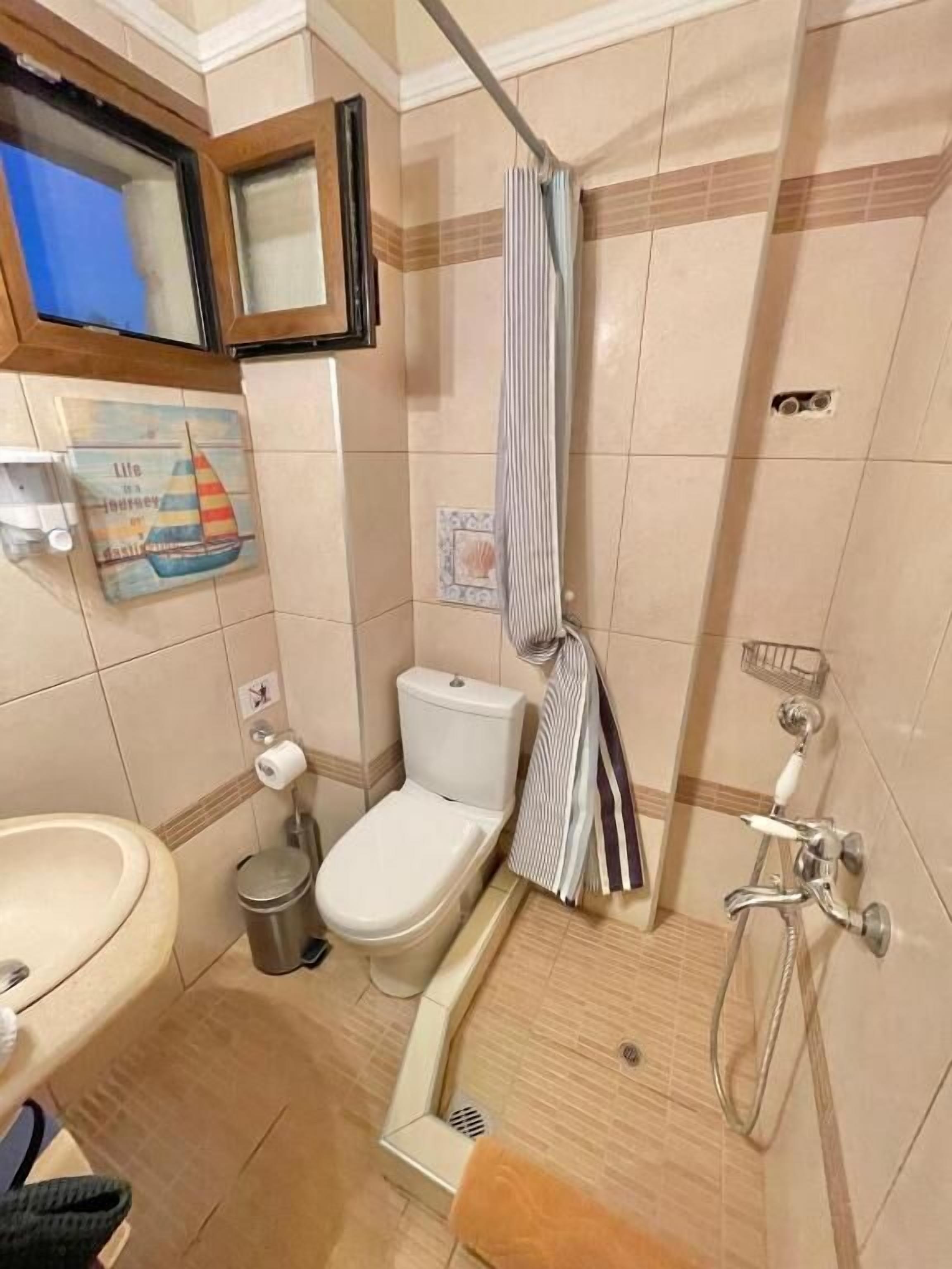 Un baño con inodoro, lavabo, ducha y un perchero para toallas.