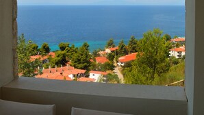 A view from a window overlooking a coastal town with red-roofed buildings and a clear blue sky. - Palamidi Apartments (Kassandra)