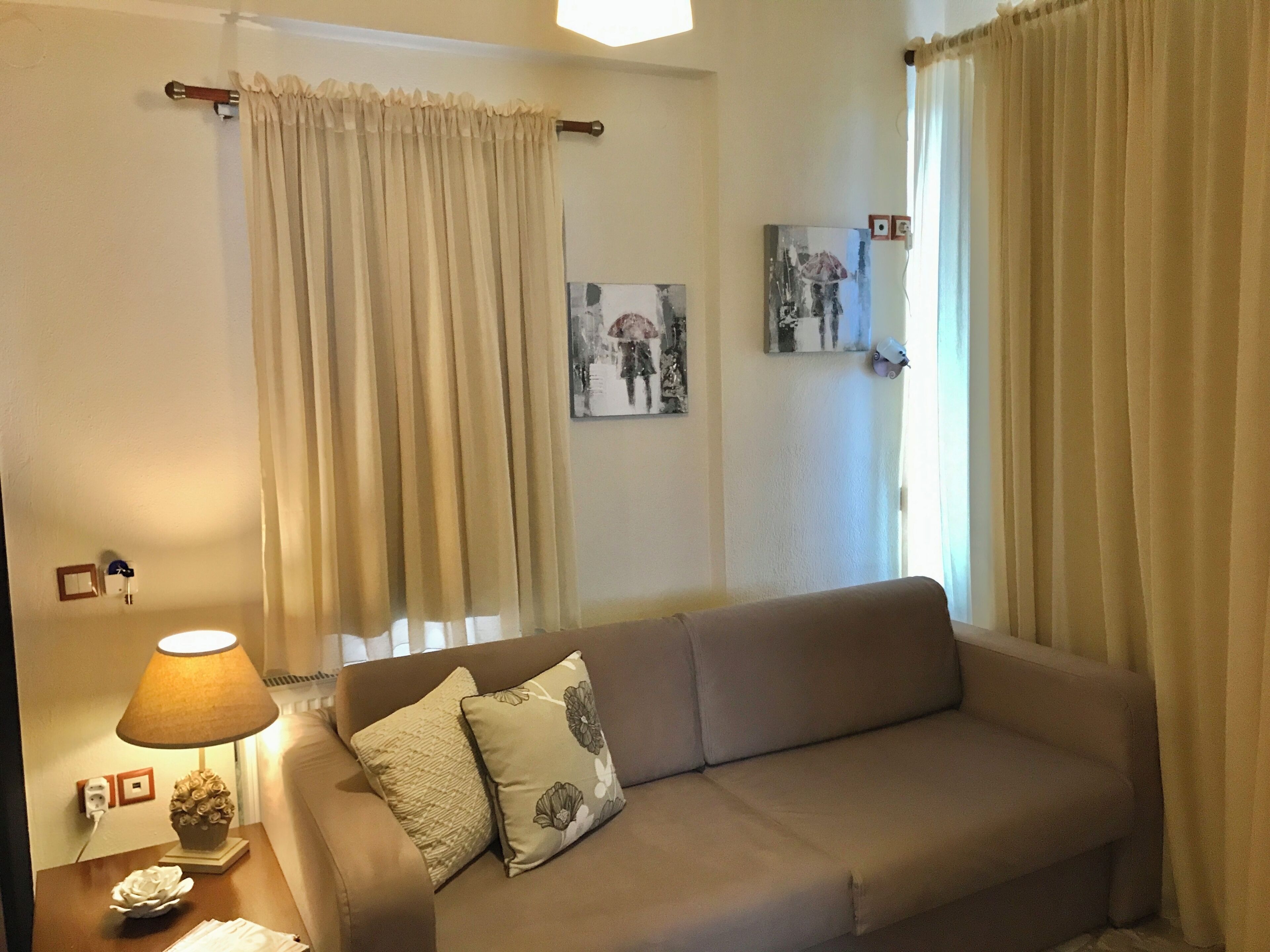 Un salon avec un canapé, une lampe et un tableau au mur.