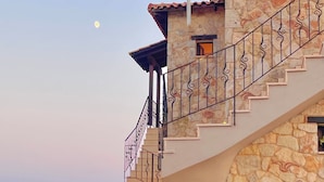A stone building with a staircase leading to a balcony. - Palamidi Apartments (Kassandra)
