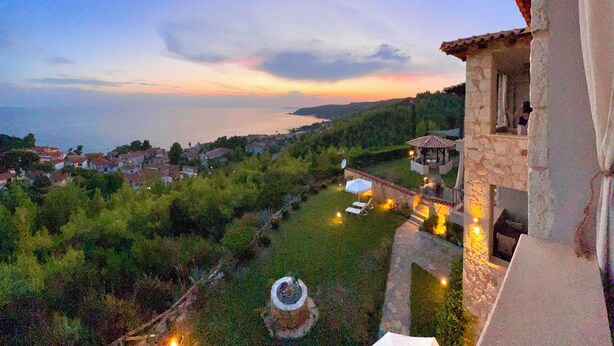 A stone building with a balcony overlooking a coastal landscape during sunset. - Palamidi Apartments (Kassandra)