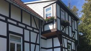 Un bâtiment traditionnel à colombages, doté d’un toit en tuiles, de lucarnes et de jardinières.