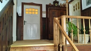 Un escalier en bois mène à une porte dotée d’un cadre blanc et à une fenêtre aux carreaux jaunes.