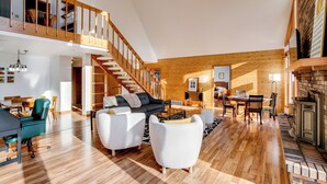 Ein geräumiger Wohnbereich mit einer Holztreppe, einem Kamin und einem Essbereich mit moderner Möbel.