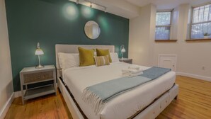 Ein Schlafzimmer mit Bett, Nachttischen, einem Spiegel und einem Fenster.