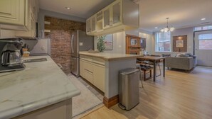 Eine moderne Küche mit Kochinsel, ein Essbereich mit Holztisch und Stühlen sowie eine Wohnarea mit Sofa und Fernseher.