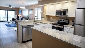 A modern kitchen with granite countertops, stainless steel appliances, and a view to the outside. - Panoramic Fort Myers Beachfront Condo - Private Sunset Views (Fort Myers Beach)