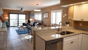 A modern kitchen with granite countertops, a dishwasher, and white cabinets. - Panoramic Fort Myers Beachfront Condo - Private Sunset Views (Fort Myers Beach)