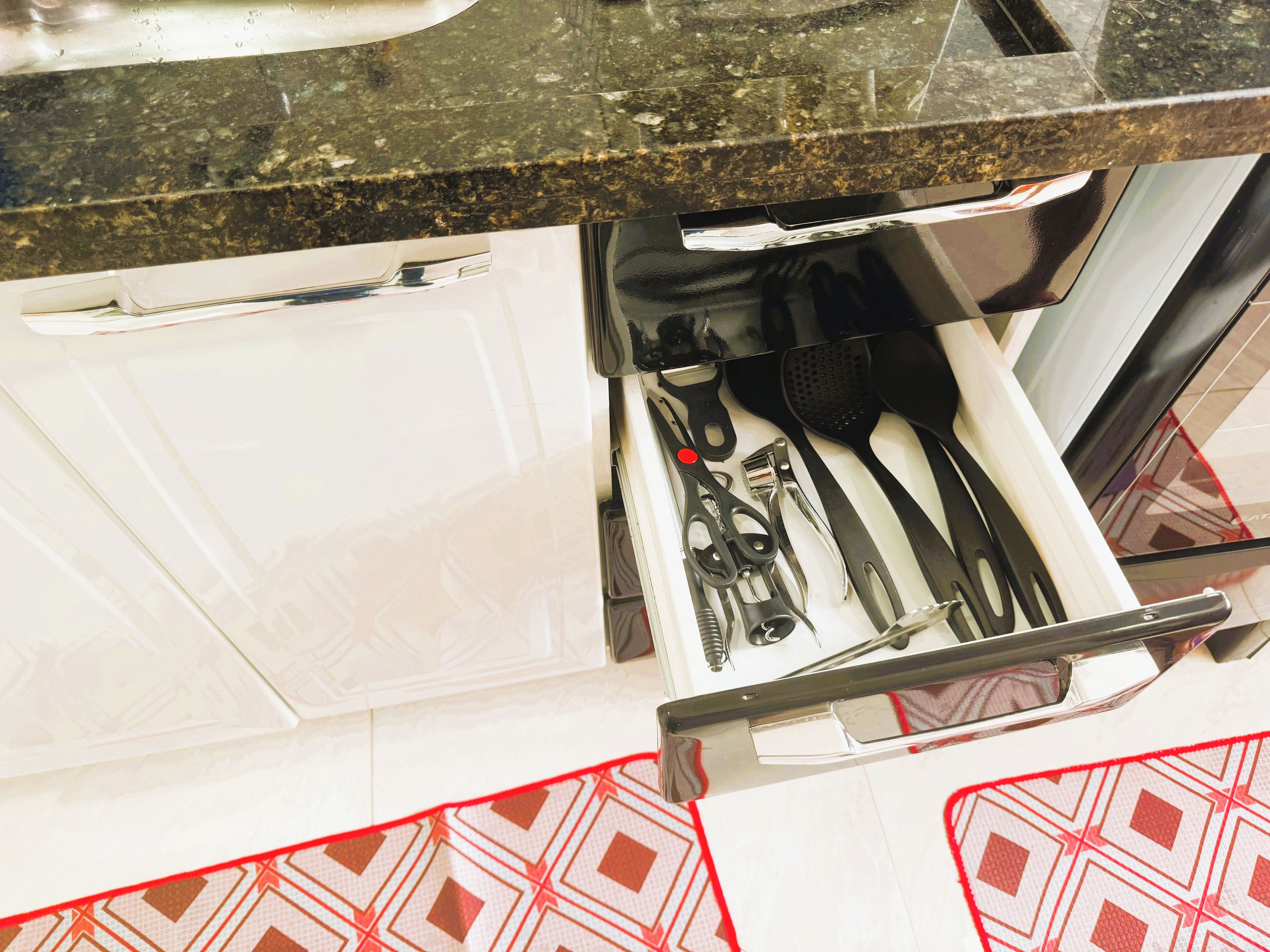 Un cajón con utensilios de cocina, incluyendo tijeras, una espátula y un rallador.