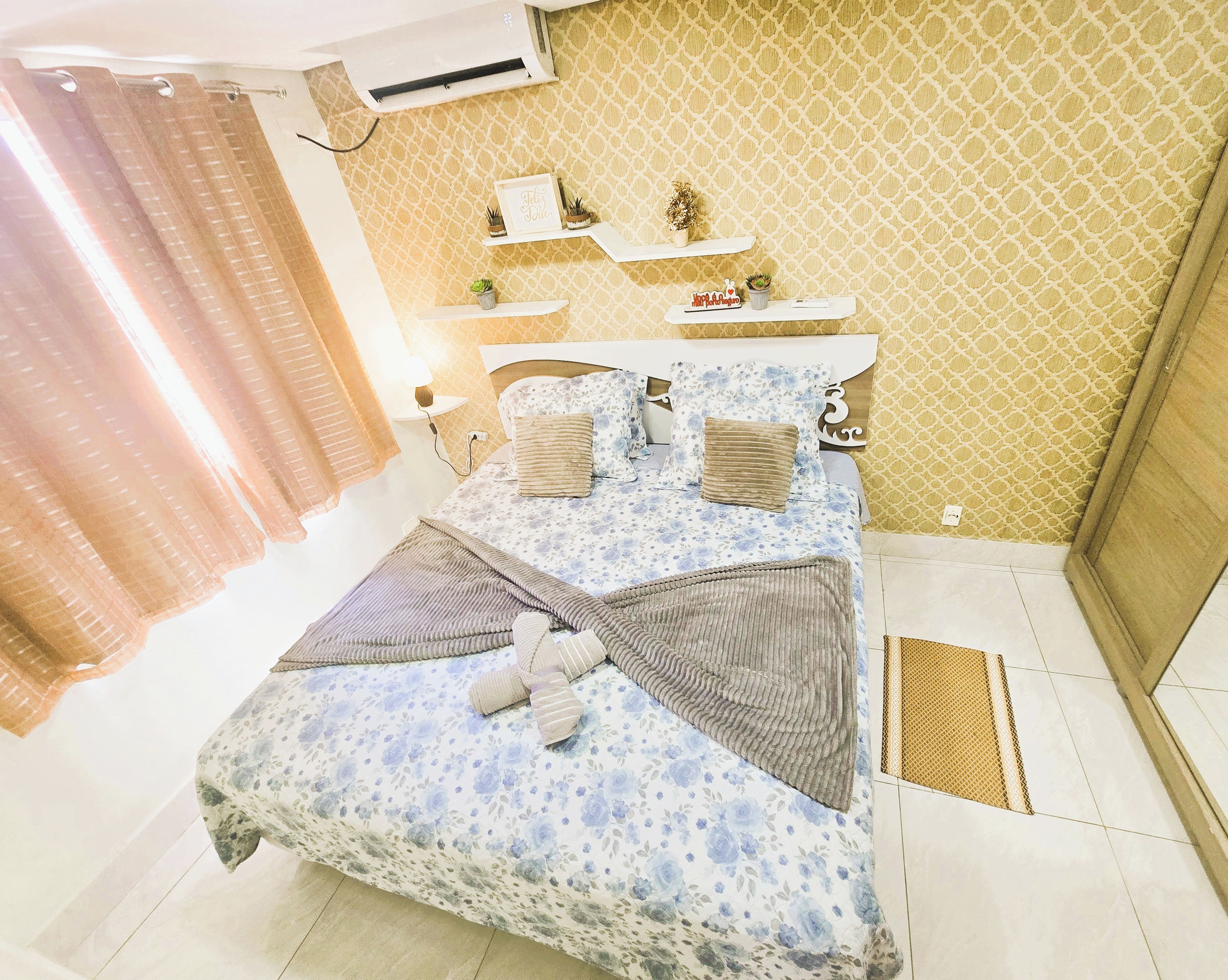 Une chambre à coucher comprenant un lit, des tables de chevet, une étagère avec des objets décoratifs et un mur orné d’un motif.