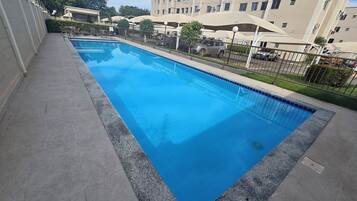 Ein rechteckiger Pool mit einer gefliesten Kante, umgeben von einer Betonplattform.