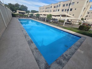 Piscina rectangular con borde de azulejos, rodeada por una plataforma de hormigón.