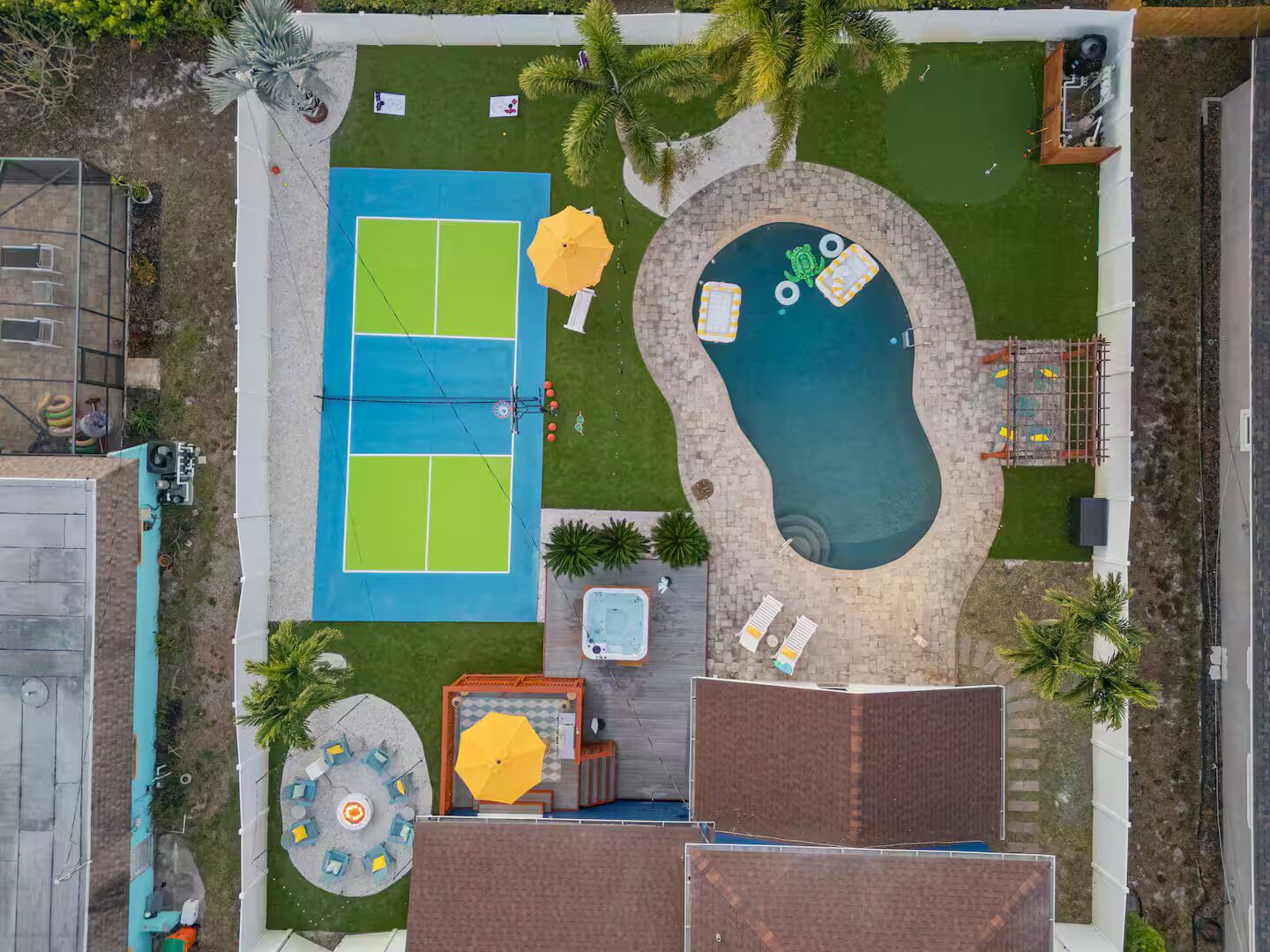 Vue aérienne d’une cour arrière comprenant un court de tennis, une piscine et un jacuzzi.