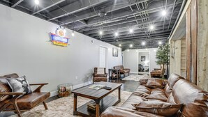 A spacious living room with leather furniture, a coffee table, and a sign advertising used cars.