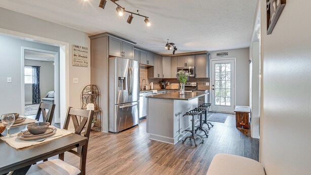 A modern kitchen with stainless steel appliances, a central island, and bar stools.