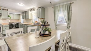 Una cocina con una isla central, electrodomésticos integrados y un comedor con sillas blancas.