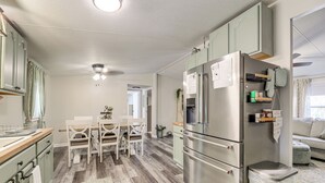 Una cocina compacta con refrigerador, una mesa de comedor con sillas y un pequeño bote de basura.