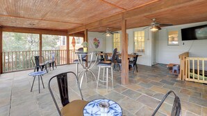 Ein überdachter Patio-Bereich mit Steinböden, Metallstühlen, einem Tisch und einem Deckenventilator.