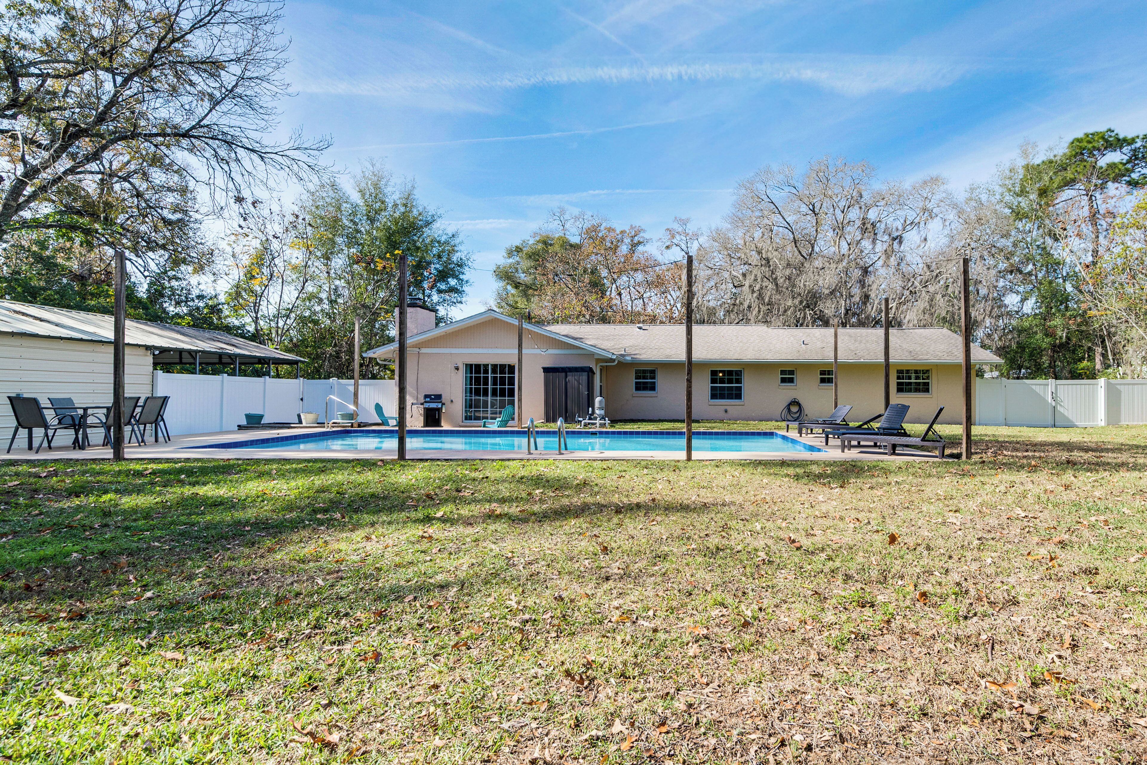 Une maison avec une piscine, un patio couvert et une cour clôturée.