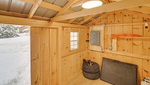 L’intérieur d’une cabane en bois, avec une fenêtre, une porte, un radiateur et un pneu.
