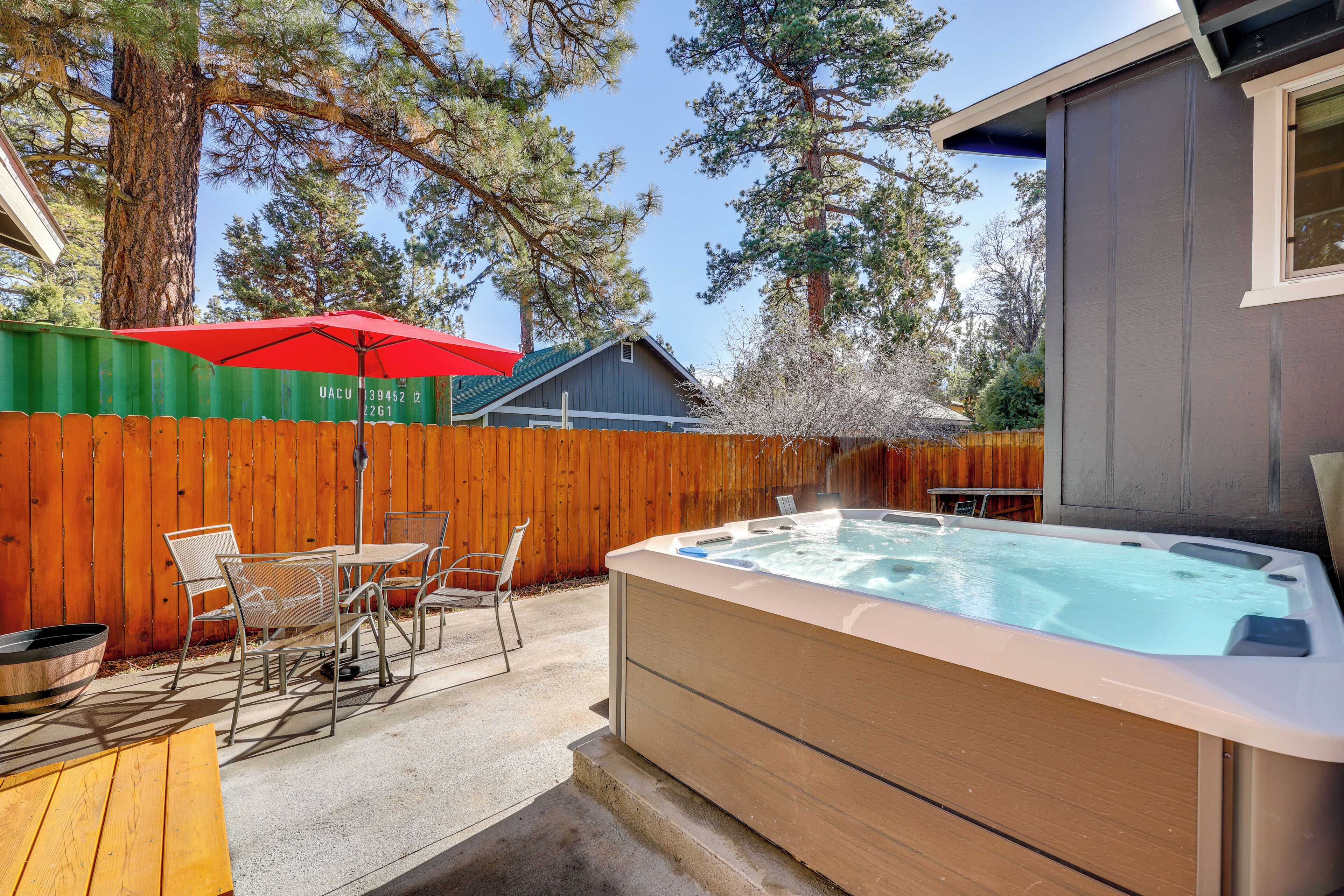 Ein Garten mit Whirlpool, Gartenmöbeln und Holzzaun.
