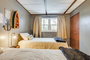 A room with two beds, a wooden shelf with books, a lamp, and a window with curtains. - George Lake Views & Access! Family Condo By Trails (Rhinelander)