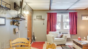 Tunnelmallinen olohuone, jossa on puinen ruokapöytä, valkoinen sohva ja punainen matto.