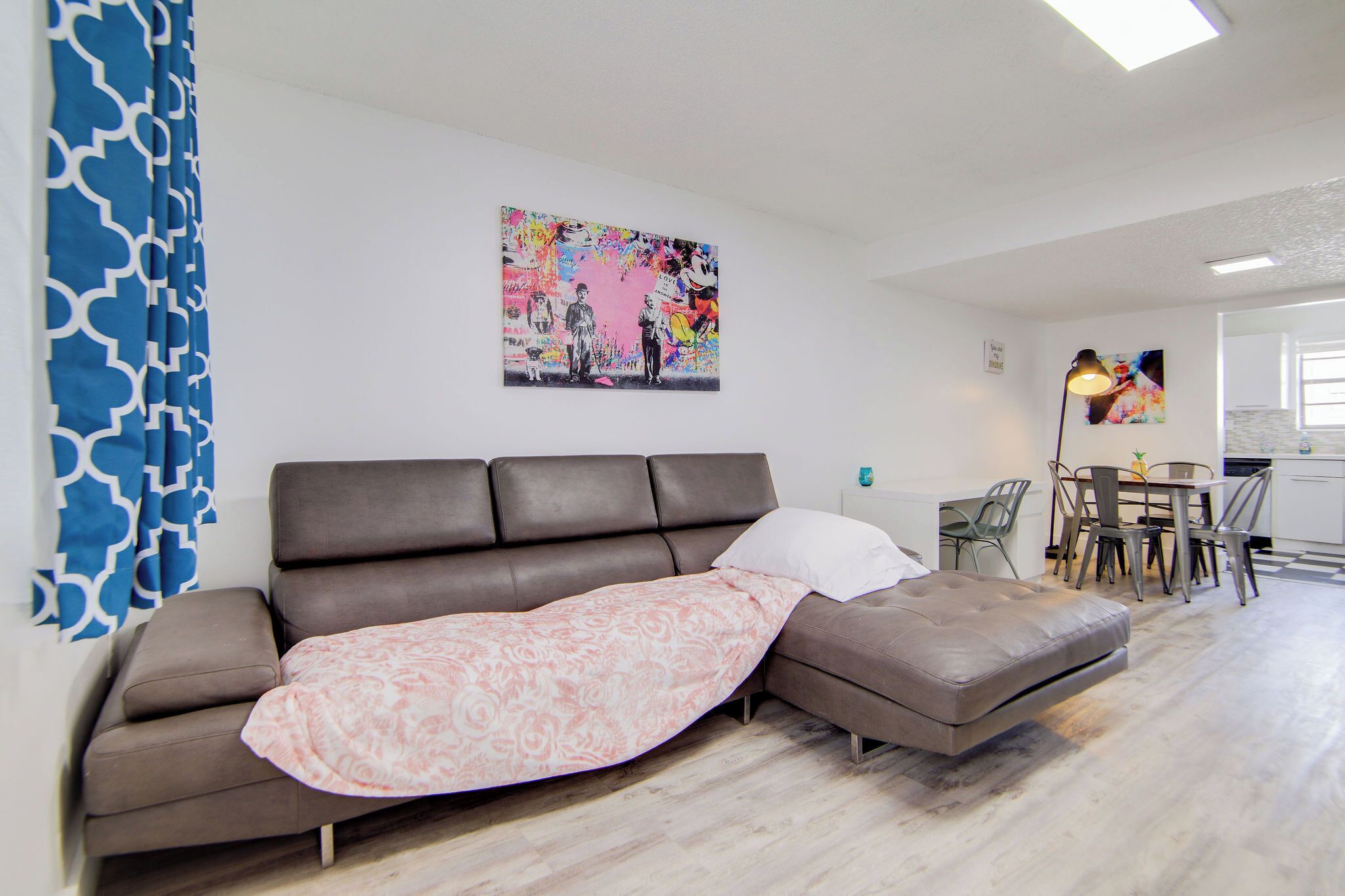 Un salon moderne avec un canapé d’angle, un coin repas et une cuisine en arrière-plan.