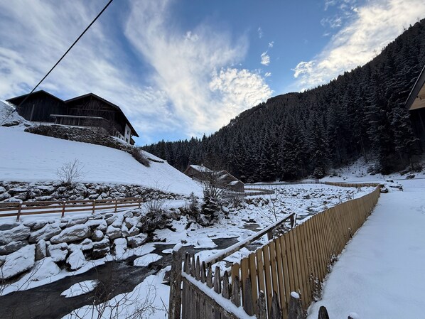Paisaje nevado con casas de madera, un muro de piedra y una valla de madera.
