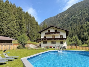 A two-story building with a swimming pool in front. - Cozy 6-person vacation apartment in the Pitztal, quiet and close to nature (Jerzens)