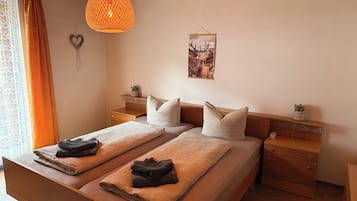 Ein Doppelbett mit zwei Kissen, ein Nachttisch mit Pflanze, eine Hängelampe und ein Wandbild.