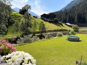Ländliche Landschaft mit Schwimmbad, Holzhaus und Berg im Hintergrund.