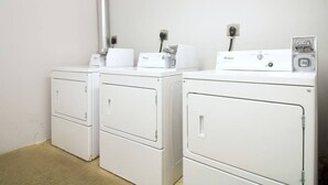 A laundry room with two white Whirlpool washers and dryers, a metal vent, and a power outlet. - Simple Studio -Walk to MGH, Beacon Hill, North End (Boston)