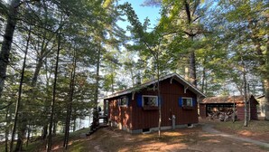 A rustic cabin with a wooden exterior, a porch, and a visible chimney. - Chalet on the Lake, Fireplace, Washer/Dryer, Snowmobile, ATV, Sleeps 8 (Woodruff)