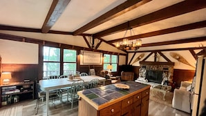 A rustic kitchen with a large island, wooden beams, and a stone fireplace. - Chalet on the Lake, Fireplace, Washer/Dryer, Snowmobile, ATV, Sleeps 8 (Woodruff)